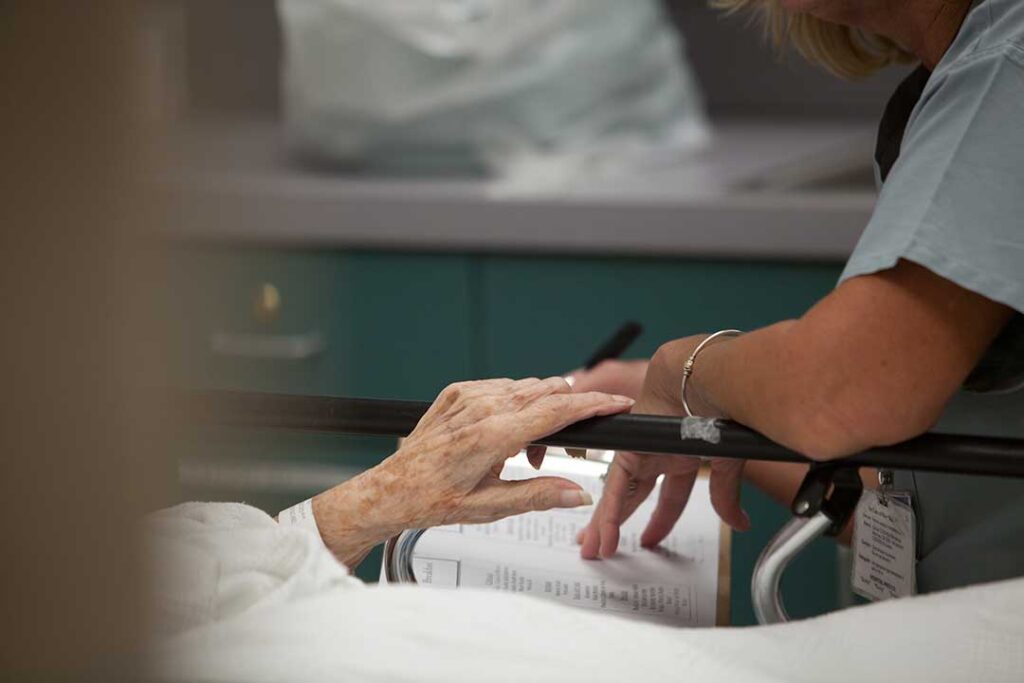 An elderly person smiling with a caregiver in a cozy, bright living room setting.